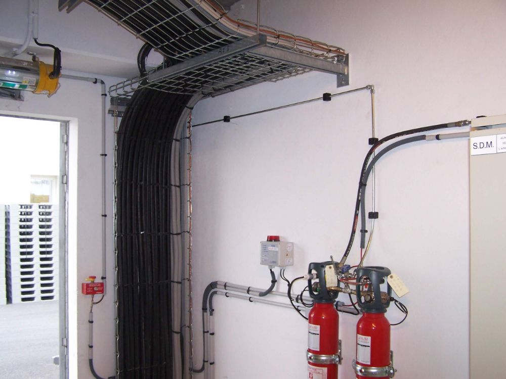 SYSTEME INDIRECT D'EXTINCTION AUTOMATIQUE TRACEFLAM POUR LA PROTECTION D'UNE ARMOIRE ELECTRIQUE cette installation est composée de 2 bouteilles de CO² qui sont continuellement surveillées par le système électronique DIMES permettant la mesure simultanée et en temps réel du contenu des bouteilles de CO². Ce système permet la protection d'une armoire électrique dans laquelle on a installé le tube Firedetec (détecteur de feux réalisé en polymères spéciaux qui réagit lorsqu'un feu se déclare et atteint le tube, la paroi du conduit s'amincit) le CO² est alors diffusé par l'intermédiaire d'une rampe de diffusion avec tromblons, garantissant une extinction rapide