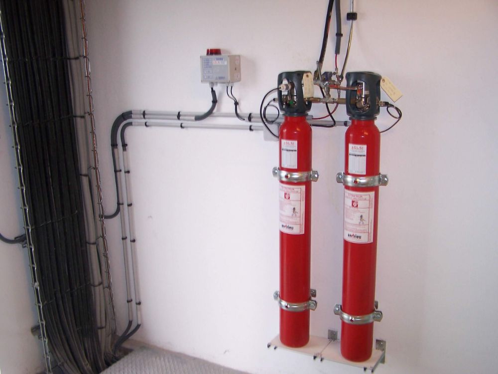 SYSTEME INDIRECT D'EXTINCTION AUTOMATIQUE TRACEFLAM POUR LA PROTECTION D'UNE ARMOIRE ELECTRIQUE cette installation est composée de 2 bouteilles de CO² qui sont continuellement surveillées par le système électronique DIMES permettant la mesure simultanée et en temps réel du contenu des bouteilles de CO². Ce système permet la protection d'une armoire électrique dans laquelle on a installé le tube Firedetec (détecteur de feux réalisé en polymères spéciaux qui réagit lorsqu'un feu se déclare et atteint le tube, la paroi du conduit s'amincit) le CO² est alors diffusé par l'intermédiaire d'une rampe de diffusion avec tromblons, garantissant une extinction rapide